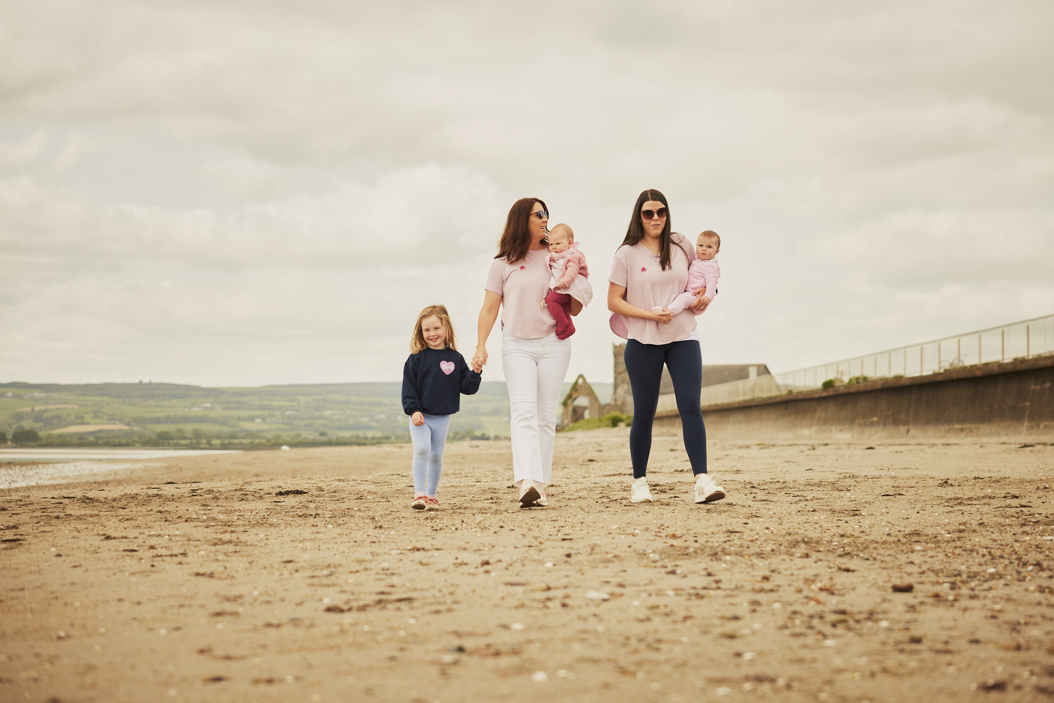 Family playing on beach wearing feed me mother apparel.